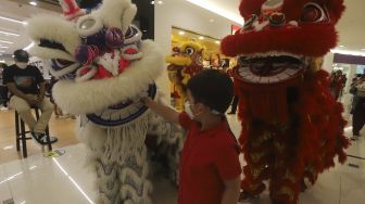 Seorang anak memberikan angpao kepada Barongsai saat beraksi menghibur pengunjung dalam pertunjukan "Barongsai Spectacles" di Mal Senayan City, Jakarta, Jumat (12/2/2021). [Suara.com/Angga Budhiyanto]