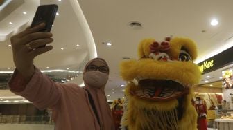 Seorang pengunjung berswafoto bersama Barongsai saat beraksi menghibur pengunjung dalam pertunjukan "Barongsai Spectacles" di Mal Senayan City, Jakarta, Jumat (12/2/2021). [Suara.com/Angga Budhiyanto]