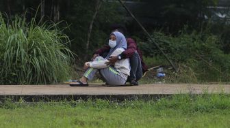 Keluarga menyaksikan dari kejauhan pemakaman jenazah korban COVID-19 di TPU Bambu Apus, Jakarta Timur, Sabtu (13/2/2021). [Suara.com/Angga Budhiyanto]