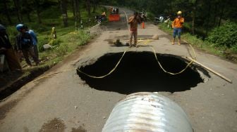 Sejumlah pekerja memperbaiki jalan yang berlubang di jalan provinsi penghubung Brebes dan Tegal, Desa Batursari, Sirampog, Brebes, Jawa Tengah, Minggu (14/2/2021). ANTARA FOTO/Oky Lukmansyah
