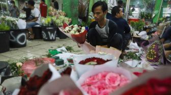 Pedagang membungkus bunga di Pasar Bunga Rawa Belong, Jakarta Barat, Minggu (14/2/2021). [Suara.com/Alfian Winanto]