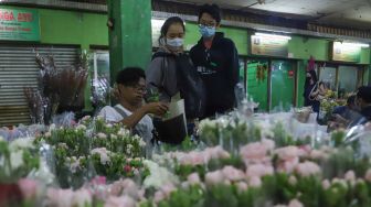 Pedagang membungkus bunga untuk pembeli di Pasar Bunga Rawa Belong, Jakarta Barat, Minggu (14/2/2021). [Suara.com/Alfian Winanto]