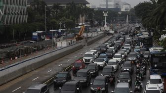 Sejumlah kendaraan melintas di samping pembangunan proyek MRT Fase II Bundaran HI-Harmoni di Jalan M.H Thamrin, Jakarta, Selasa (16/2/2021). [Suara.com/Angga Budhiyanto]