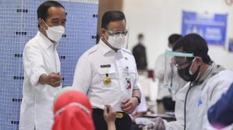 Presiden Joko Widodo (kiri) didampingi Gubernur DKI Jakarta Anies Baswedan (kedua kiri) meninjau vaksinasi COVID-19 massal bagi pedagang di Pasar Tanah Abang Blok A, Jakarta, Rabu (17/2/2021). ANTARA FOTO/Hafidz Mubarak 
