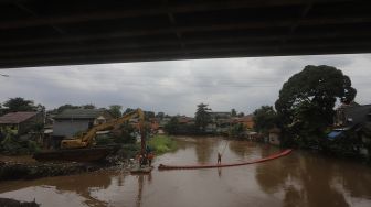 Petugas UPK Badan Air Kecamatan Makasar dibantu alat berat melakukan pengerukan sampah di Kali Sunter, Kelurahan Cipinang Melayu, Jakarta, Jumat (19/2/2021). [Suara.com/Angga Budhiyanto]