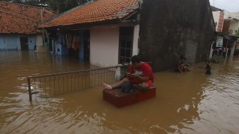 Warga beraktivitas saat banjir merendam Kelurahan Cipinang Melayu, Jakarta, Jumat (19/2/2021). [Suara.com/Angga Budhiyanto]