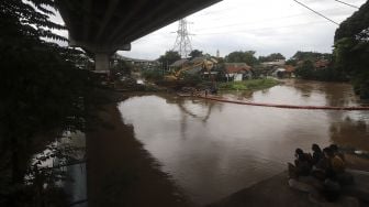 Sejumlah warga menyaksikan proses pengerukan sampah di Kali Sunter, Kelurahan Cipinang Melayu, Jakarta, Jumat (19/2/2021). [Suara.com/Angga Budhiyanto]