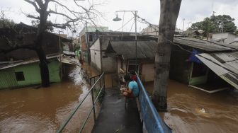 Warga beraktivitas saat banjir merendam Kelurahan Cipinang Muara, Jakarta, Jumat (19/2/2021). [Suara.com/Angga Budhiyanto]