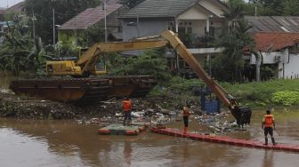 Petugas UPK Badan Air Kecamatan Makasar dibantu alat berat melakukan pengerukan sampah di Kali Sunter, Kelurahan Cipinang Melayu, Jakarta, Jumat (19/2/2021). [Suara.com/Angga Budhiyanto]