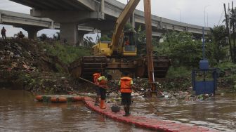 Petugas UPK Badan Air Kecamatan Makasar dibantu alat berat melakukan pengerukan sampah di Kali Sunter, Kelurahan Cipinang Melayu, Jakarta, Jumat (19/2/2021). [Suara.com/Angga Budhiyanto]