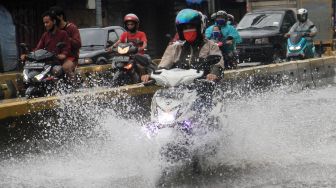 Pengendara melintas  di Jalan Jatinegara Barat, Jakarta Timur yang tersendat akibat sebagian badan jalan terendam banjir luapan Sungai Ciliwung dengan ketinggian sekitar 20 sentimeter, Sabtu (20/2). [Suara.com/Oke Atmaja]
