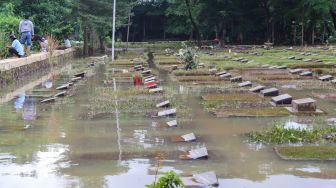 Penampakan area makam yang terendam banjir di TPU Jeruk Purut, Jakarta Selatan, Sabtu (20/2/2021). [Suara.com/Alfian Winanto]