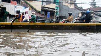 Suasana arus lalu lintas di Jalan Jatinegara Barat, Jakarta Timur yang tersendat akibat sebagian badan jalan terendam banjir luapan Sungai Ciliwung dengan ketinggian sekitar 20 sentimeter, Sabtu (20/2). [Suara.com/Oke Atmaja]
