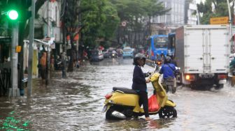 Pengendara melintas di Jalan Jatinegara Barat, Jakarta Timur yang tersendat akibat sebagian badan jalan terendam banjir luapan Sungai Ciliwung dengan ketinggian sekitar 20 sentimeter, Sabtu (20/2). [Suara.com/Oke Atmaja]
