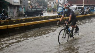 Pesepeda melintas di Jalan Jatinegara Barat, Jakarta Timur yang tersendat akibat sebagian badan jalan terendam banjir luapan Sungai Ciliwung dengan ketinggian sekitar 20 sentimeter, Sabtu (20/2). [Suara.com/Oke Atmaja]
