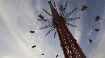 Pengunjung menaiki wahana 'sky flyer' di Taman Bollywood, Dubai, pada (18/2/2021). [GIUSEPPE CACACE / AFP]