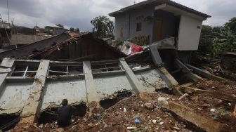 Warga membersihkan puing-puing reruntuhan di rumahnya yang tertimpa tanah longsor di Kelurahan Bangka, Mampang Prapatan, Jakarta, Minggu (21/2/2021). [Suara.com/Angga Budhiyanto]