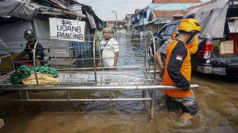 Relawan membawa keranda jenazah orang meninggal usai dimakamkan melewati jalan yang tergenang banjir di Tempat Pemakaman Umum (TPU), Pekalongan, Jawa Tengah, Minggu (21/2/2021). [ANTARA FOTO/Harviyan Perdana Putra]