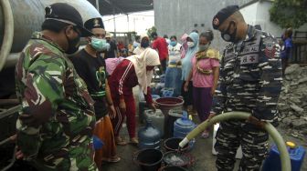 Personel TNI mengisi air bersih ke dalam ember di Kelurahan Muarareja, Tegal, Jawa Tengah, Minggu (21/2/2021). [ANTARA FOTO/Oky Lukmansyah]