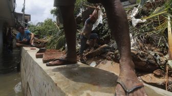 Warga membersihkan puing-puing reruntuhan di rumahnya yang tertimpa tanah longsor di Kelurahan Bangka, Mampang Prapatan, Jakarta, Minggu (21/2/2021). [Suara.com/Angga Budhiyanto]