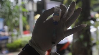 Paramedis dari pusat kesehatan hewan (Puskewan) Dinas Ketahanan Pangan, Kelautan dan Pertanian Kota Administrasi Jakarta Selatan menyiapkan vaksin anti rabies untuk disuntikkan kepada hewan peliharaan terdampak banjir di Kantor Kelurahan Pela Mampang, Jakarta, Senin (22/2/2021). [Suara.com/Angga Budhiyanto]