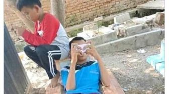 Viral Bocah Asyik Mabar Sambil Rebahan di Makam, Publik: Enggak Ada Akhlak!