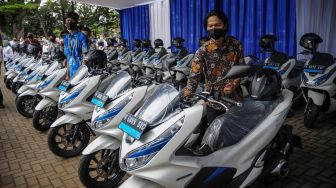 Petugas memeriksa kompartemen motor listrik saat penyerahan motor listrik bagi Aparatur Sipil Negara (ASN) di Balai Kota Bandung, Jawa Barat, Rabu (24/2/2021).  [ANTARA FOTO/Raisan Al Farisi]