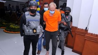 Warga negara Rusia Andrei Kovalenka alias Andrew Ayer (tengah) digiring petugas saat rilis di Kantor Imigrasi Kelas I Khusus TPI Ngurah Rai, Badung, Bali, Rabu (24/2/2021). [ANTARA FOTO/Fikri Yusuf]
