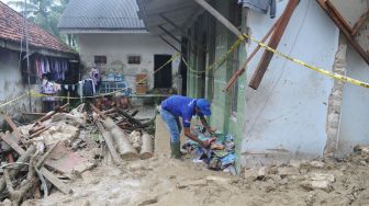 Anggota Tagana membersihkan puing Pesantren An Nidhoniyah yang tertimbun tanah longsor di Desa Bindang, Pamekasan, Jawa Timur, Rabu (24/2/2021). [ANTARA FOTO/Saiful Bahri]
