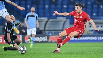 Pemain depan Bayern Munich Robert Lewandowski menembak untuk membuka skor selama pertandingan leg pertama babak 16 besar Liga Champions Lazio melawan Bayern Munich di Stadion Olimpico, Roma, Rabu (24/2/2021) dini hari WIB. Alberto PIZZOLI / AFP
