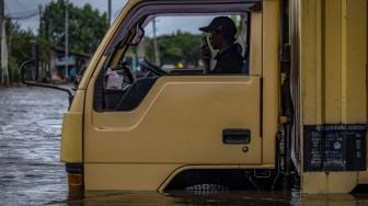 Seorang sopir menghubungi rekannya setelah truknya mogok terjebak banjir yang merendam Jalur Pantura Kaligawe-Genuk, Semarang, Jawa Tengah, Rabu (24/2/2021).  ANTARA FOTO/Aji Styawan