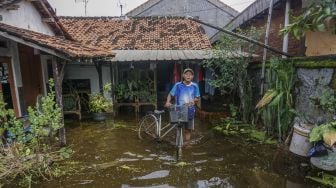 Warga mendorong sepedanya melewati genangan banjir di Tirto, Kabupaten Pekalongan, Jawa Tengah, Jumat (26/2/2021). ANTARA FOTO/Harviyan Perdana Putra
