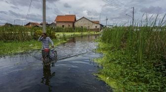 Warga mendorong sepedanya melewati genangan banjir di Tirto, Kabupaten Pekalongan, Jawa Tengah, Jumat (26/2/2021). ANTARA FOTO/Harviyan Perdana Putra
