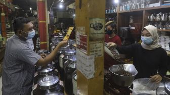 Penjual biji kopi melayani pembeli di salah satu gerai penjual biji kopi di Pasar Santa, Jakarta, Rabu (3/3/2021). [Suara.com/Angga Budhiyanto]