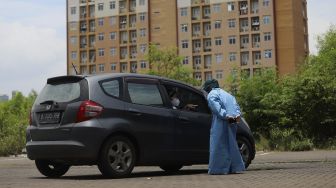 Petugas kesehatan melayani warga yang berada di atas kendaraan usai melakukan vaksinasi COVID-19 dengan sistem 'drive thru' di area parkir Hall C JIExpo Kemayoran, Jakarta, Rabu (3/3/2021). [Suara.com/Angga Budhiyanto]