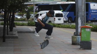 Seorang anak bermain papan luncur (skateboard) di trotoar kawasan Bundaran HI, Jakarta, Jumat (5/3/2021). [Suara.com/Angga Budhiyanto]