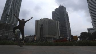 Seorang anak bermain papan luncur (skateboard) di trotoar kawasan Bundaran HI, Jakarta, Jumat (5/3/2021). [Suara.com/Angga Budhiyanto]