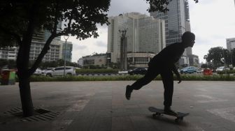 Seorang anak bermain papan luncur (skateboard) di trotoar kawasan Bundaran HI, Jakarta, Jumat (5/3/2021). [Suara.com/Angga Budhiyanto]