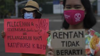 Massa yang tergabung dalam Perempuan Mahardhika membawa poster saat melakukan aksi memperingati Hari Perempuan Internasional di kawasan Patung Kuda Arjuna Wiwaha, Jakarta, Senin (8/3/2021). [Suara.com/Angga Budhiyanto]