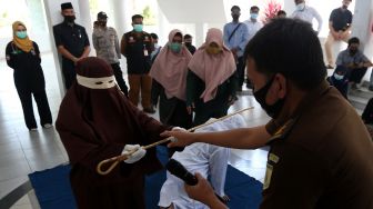 Algojo (kiri) menyerahkan kembali rotan yang digunakan untuk mengeksekusi cambuk terpidana pelanggar peraturan daerah (qanun) nomor 6/2020 tentang hukum jinayat kepada petugas jaksa di Banda Aceh, Aceh, Senin (8/3/2021). ANTARA FOTO / Irwansyah Putra