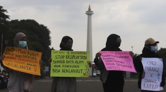 Sejumlah massa yang tergabung dalam Perempuan Mahardhika membawa poster saat melakukan aksi memperingati Hari Perempuan Internasional di kawasan Patung Kuda Arjuna Wiwaha, Jakarta, Senin (8/3/2021). [Suara.com/Angga Budhiyanto]