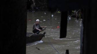 Seorang warga mengoperasikan perahu eretan untuk menyeberangi Kali Ciliwung di kawasan Manggarai, Jakarta, Selasa (9/3/2021). [Suara.com/Angga Budhiyanto]