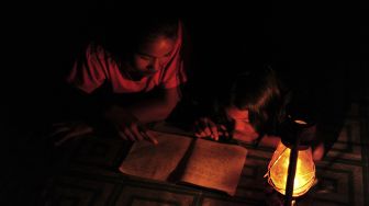 Dua anak membaca hanya diterangi lampu minyak di rumahnya yang belum mendapatkan layanan listrik di Kampung Jao, Nagari Panyubarangan, Dharmasraya, Sumatera Barat, Senin (8/3/2021).  ANTARA FOTO/Wahdi Septiawan