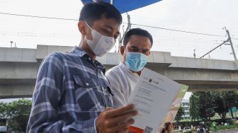Petugas Dinas Pariwisata dan Ekonomi Kreatif DKI Jakarta menjelaskan tentang destinasi wisata kepada warga saat uji coba Tourist Information Center Mobile (TICM) di Terminal Blok M, Jakarta Selatan, Jumat (12/3/2021). [Suara.com/Alfian Winanto]