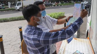 Petugas Dinas Pariwisata dan Ekonomi Kreatif DKI Jakarta menjelaskan tentang destinasi wisata kepada warga saat uji coba Tourist Information Center Mobile (TICM) di Terminal Blok M, Jakarta Selatan, Jumat (12/3/2021). [Suara.com/Alfian Winanto]