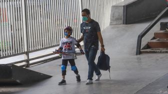 Orang tua mengajak anaknya untuk bermain skateboard di arena Skatepark Pasar Rebo, Jakarta Timur, Sabtu (13/3/2021). [Suara.com/Alfian Winanto]