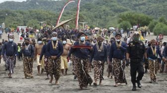 Sejumlah abdi dalem Keraton Yogyakarta membawa sesaji menuju pantai saat Prosesi Labuhan Parangkusumo di Pantai Parang Kusumo, Bantul, DI Yogyakarta, Minggu (14/3/2021). [ANTARA FOTO/Andreas Fitri Atmoko]