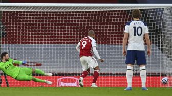 Striker Arsenal Alexandre Lacazette menembak dari titik penalti untuk mencetak gol kedua timnya saat kiper Tottenham Hotspur, Hugo Lloris (kiri) melakukan penyelaman yang salah selama pertandingan sepak bola Liga Inggris antara Arsenal dan Tottenham Hotspur di Emirates Stadium, London, pada (14/3/2021). [Julian Finney / POOL / AFP]