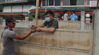 Asep (29) salah seorang penghuni rumah membeli makanan dari balik tembok beton yang menutupi rumahnya di Tajur Ciledug, Tangerang, Banten, Senin (15/3/2021). ANTARA FOTO/Muhammad Iqbal