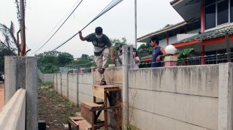 Asep (29) salah seorang penghuni rumah melompati tembok beton untuk keluar dari dalam rumahnya yang terkepung tembok beton di Tajur Ciledug, Tangerang, Banten, Senin (15/3/2021).  ANTARA FOTO/Muhammad Iqbal